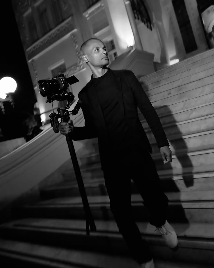 Wagner de Souza Teodoro com câmera em gimbal na escadaria de um teatro, à noite